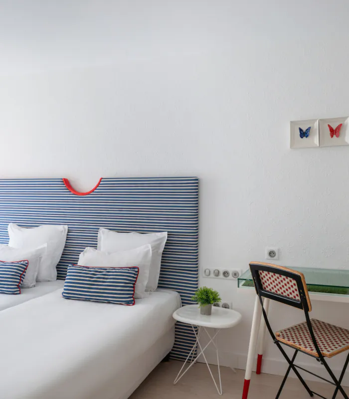 Chambre Twin lumineuse à l’Hôtel 34B avec deux lits simples, tête de lit rayée, bureau et télévision.