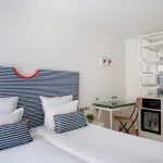 Chambre Twin lumineuse à l’Hôtel 34B avec deux lits simples, tête de lit rayée, bureau et télévision.