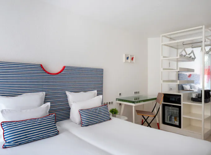Chambre Twin lumineuse à l’Hôtel 34B avec deux lits simples, tête de lit rayée, bureau et télévision.