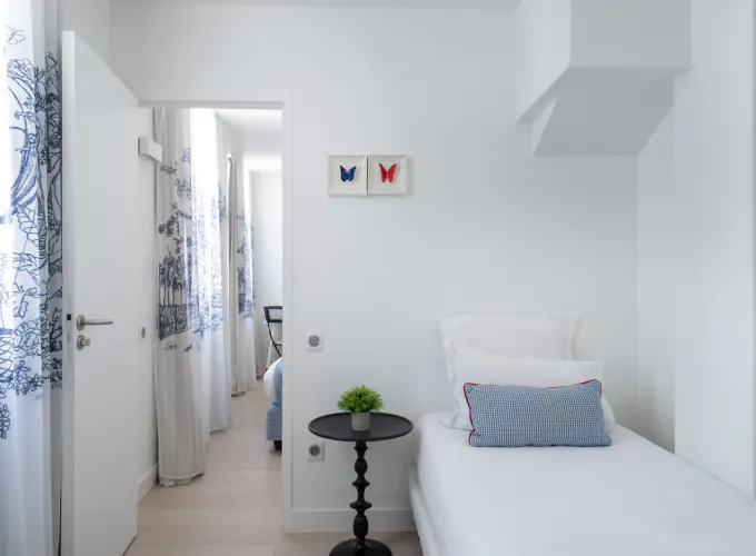 Chambre Triple à l’Hôtel 34B avec literie confortable et décoration aux tons bleus et blancs.