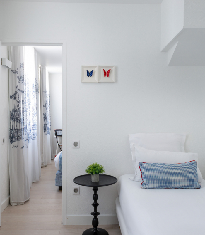 Chambre Triple à l’Hôtel 34B avec literie confortable et décoration aux tons bleus et blancs.