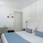 Chambre Triple à l’Hôtel 34B avec literie confortable et décoration aux tons bleus et blancs.