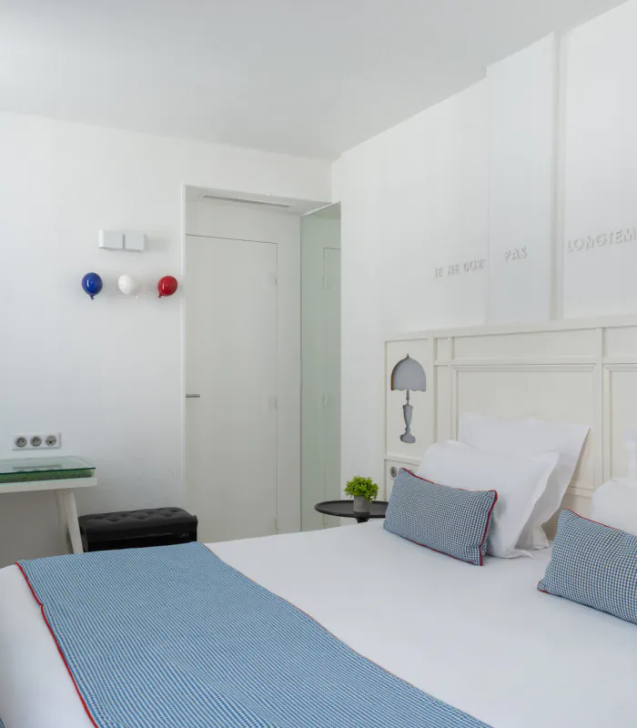Chambre Triple à l’Hôtel 34B avec literie confortable et décoration aux tons bleus et blancs.