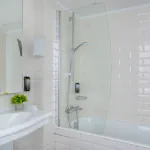 Salle de bain de la Chambre Triple à l’Hôtel 34B avec baignoire et lavabo.