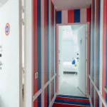 Couloir de la Chambre Familiale avec des rayures rouges, blanches et bleues et le numéro 601 sur la porte à l’Hôtel 34B