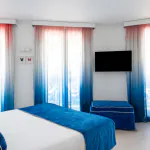 Chambre Familiale Supérieure avec un grand lit et des rideaux bleus à l’Hôtel 34B