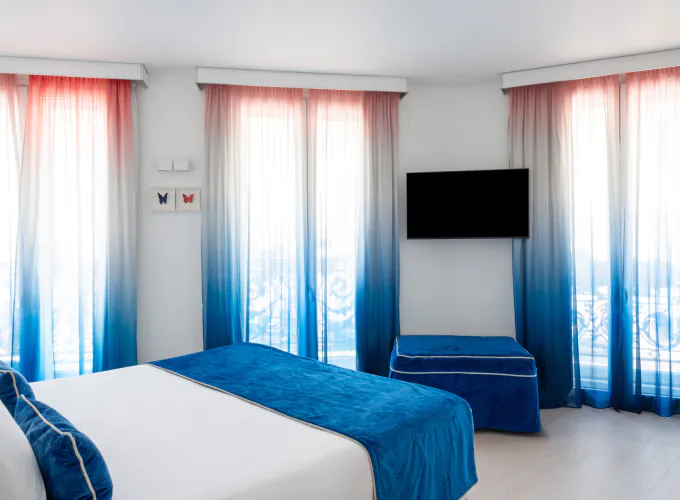 Chambre Familiale Supérieure avec un grand lit et des rideaux bleus à l’Hôtel 34B