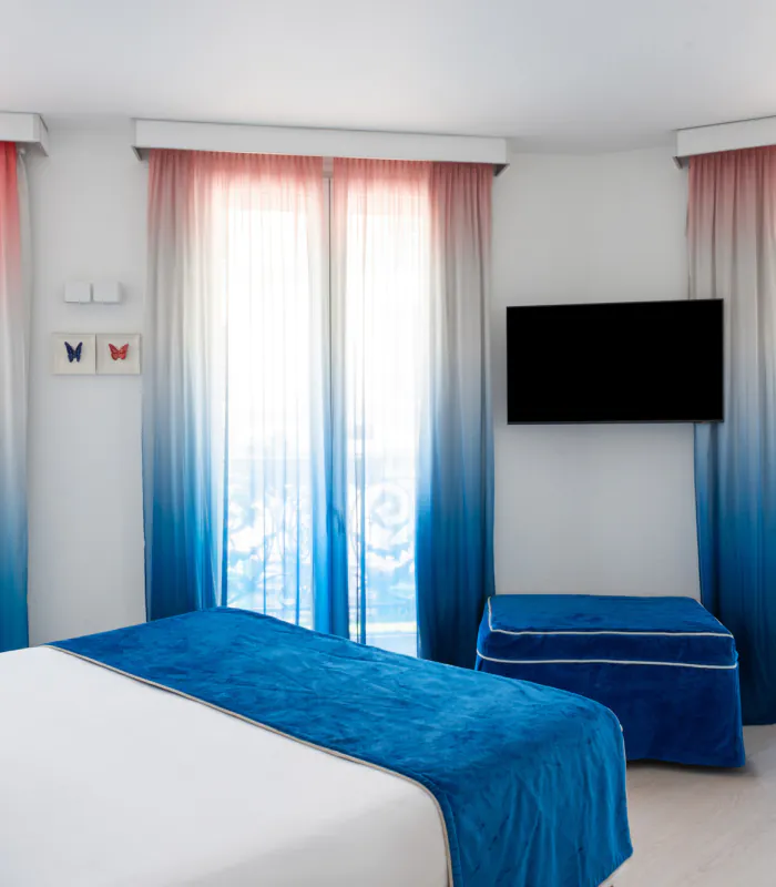Chambre Familiale Supérieure avec un grand lit et des rideaux bleus à l’Hôtel 34B