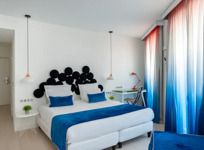 Chambre Familiale Supérieure avec un grand lit et des rideaux bleus à l’Hôtel 34B