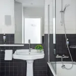 Salle de bain de la Chambre Familiale Supérieure avec des carreaux noirs et blancs et un lavabo à l’Hôtel 34B