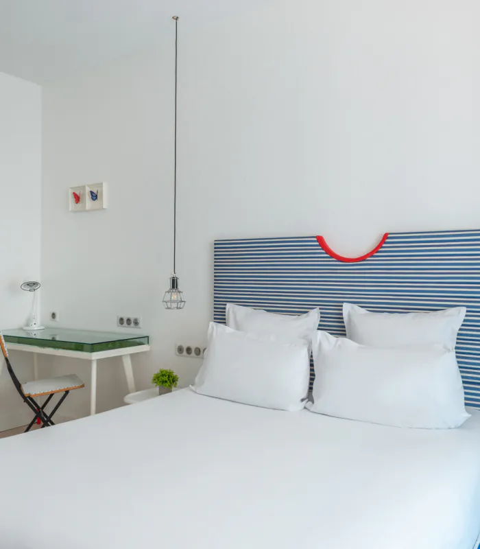 Chambre double avec tête de lit à rayures bleues et blanches à l’Hôtel 34B