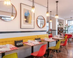 Salle de petit-déjeuner de l’hôtel Augustin à Paris avec un buffet varié, une atmosphère chaleureuse et des touches de couleur vives