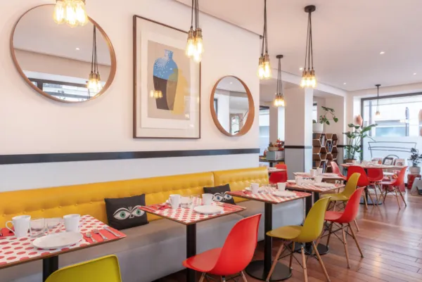 Salle de petit-déjeuner de l’hôtel Augustin à Paris avec un buffet varié, une atmosphère chaleureuse et des touches de couleur vives