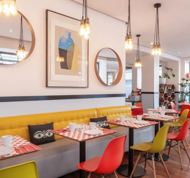 Sala colazioni dell’Hotel Augustin a Parigi con buffet vario, atmosfera accogliente e vivaci tocchi di colore