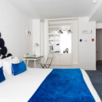 chambre double accessible avec décoration bleue et blanche et vue sur la salle de bain adaptée à l’hôtel 34b