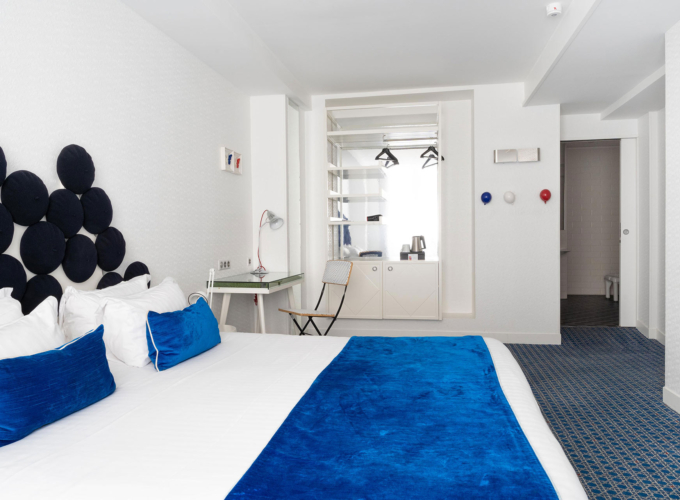 chambre double accessible avec décoration bleue et blanche et vue sur la salle de bain adaptée à l’hôtel 34b