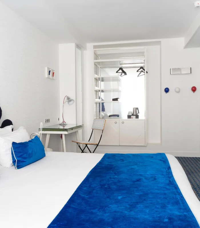 chambre double accessible avec décoration bleue et blanche et vue sur la salle de bain adaptée à l’hôtel 34b