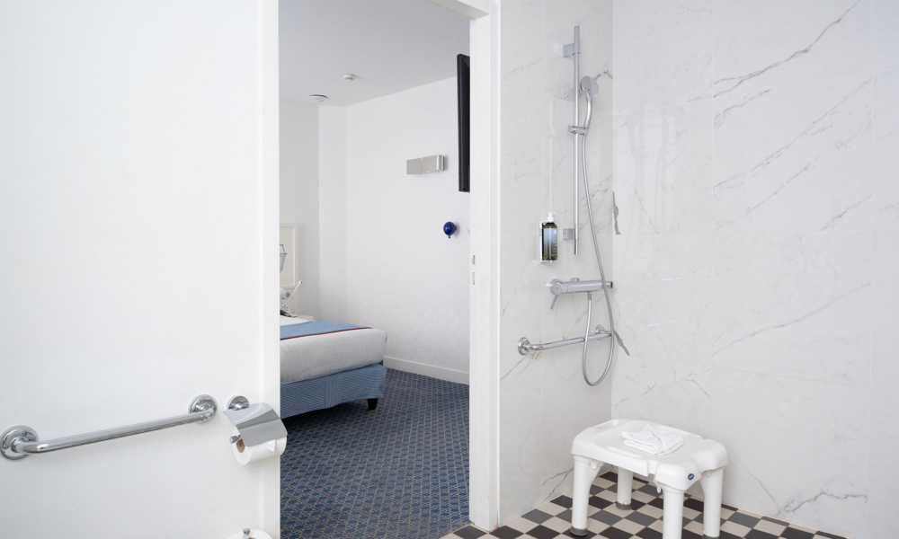 accessible bathroom with walk-in shower, seat, grab bars and view of the bedroom at the hotel 34b