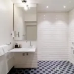 salle de bain accessible avec douche à l’italienne, siège, barres d’appui et lavabo adapté à l’hôtel 34b