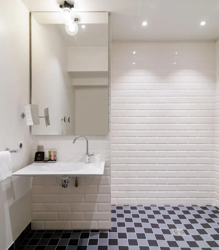 salle de bain accessible avec douche à l’italienne, siège, barres d’appui et lavabo adapté à l’hôtel 34b