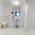 salle de bain accessible avec douche à l’italienne, siège et lavabo à l’hôtel lorette