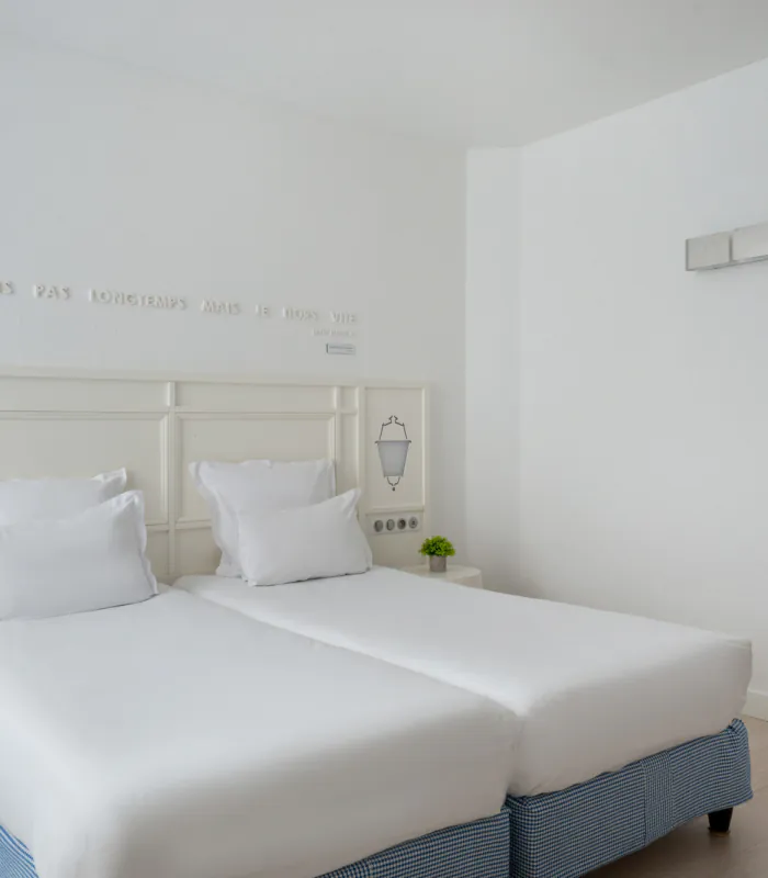 chambre twin accessible avec deux lits simples et décoration bleu clair à l’hôtel 34b