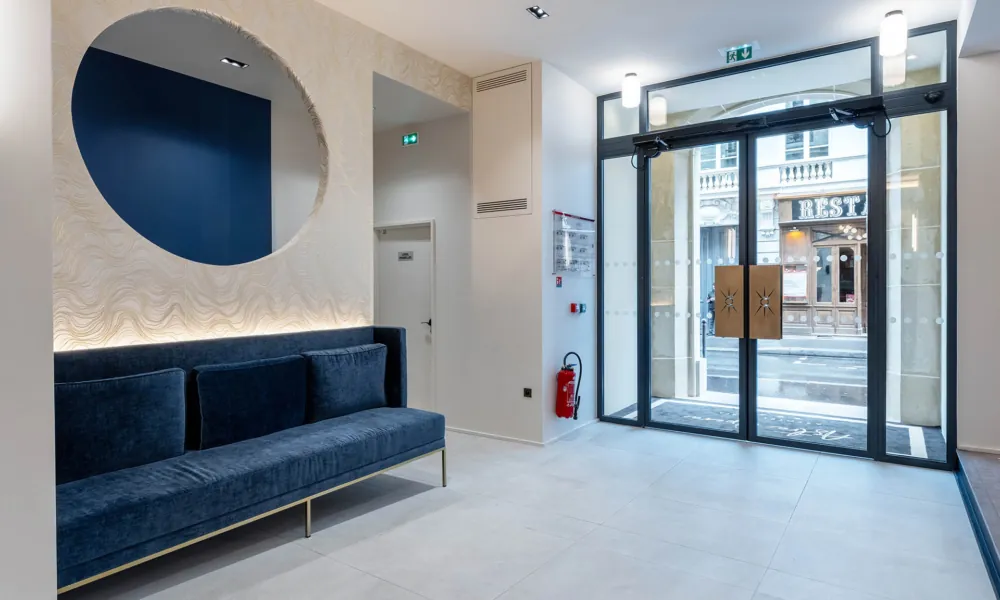 Ebenerdiger Hoteleingang mit doppelt automatischen Türen, großzügigem Raum und direkter Sicht auf die Rezeption.