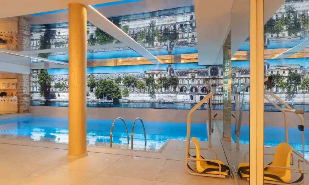 Schwimmbad in Paris mit hydraulischem Hebelift für den Zugang ins Wasser und barrierefreien Einrichtungen, darunter Duschen, Haltegriffe und angepasste Umkleiden.