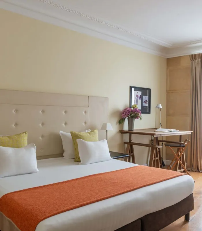 Chambre Familiale Privilège à l’hôtel Le 123 Elysées avec un grand lit, des oreillers jaunes et blancs et un bureau