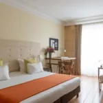 Chambre Familiale Privilège à l’hôtel Le 123 Elysées avec un grand lit, des oreillers jaunes et blancs et un bureau