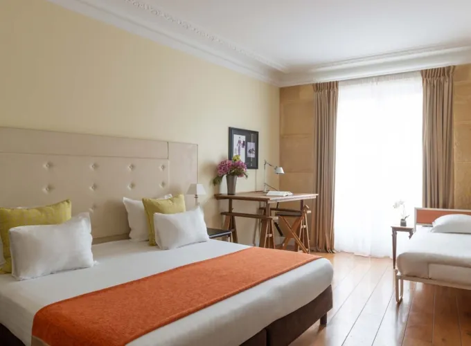 Chambre Familiale Privilège à l’hôtel Le 123 Elysées avec un grand lit, des oreillers jaunes et blancs et un bureau