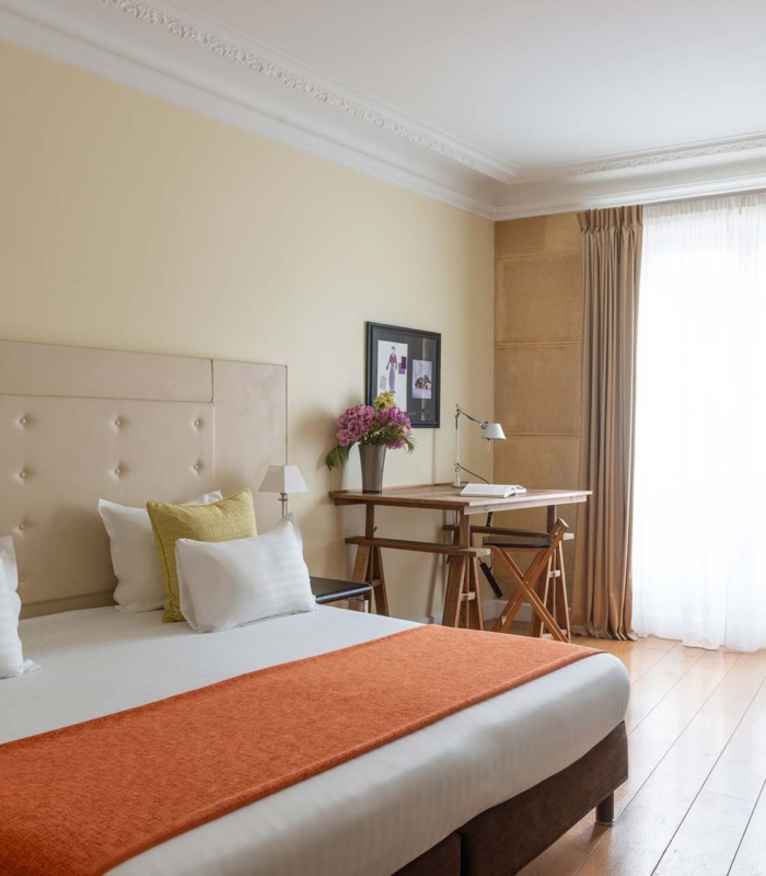 Chambre Familiale Privilège à l’hôtel Le 123 Elysées avec un grand lit, des oreillers jaunes et blancs et un bureau