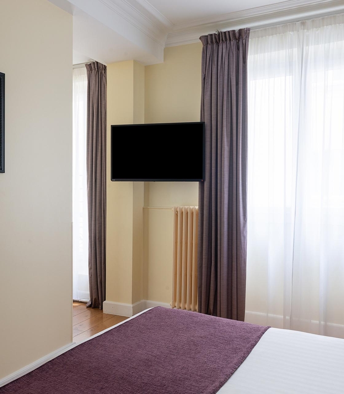 Chambre Familiale Privilège à l’hôtel Le 123 Elysées avec deux lits et une télévision