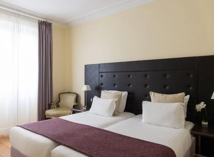 Chambre Familiale Privilège à l’hôtel Le 123 Elysées avec deux lits et une chaise