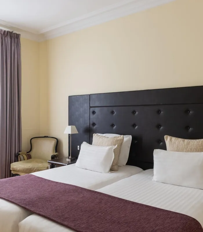 Chambre Familiale Privilège à l’hôtel Le 123 Elysées avec deux lits et une chaise