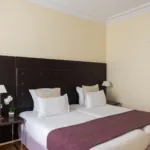 Chambre Familiale Privilège à l’hôtel Le 123 Elysées avec deux lits et une chaise