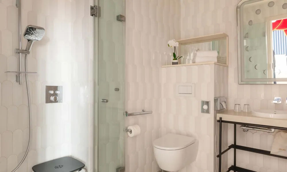 Barrierefreies Badezimmer des Hotel Astra Opéra in Paris mit ebenerdiger Dusche, Haltegriffen, zugänglichem Waschbecken und Bewegungsfläche.