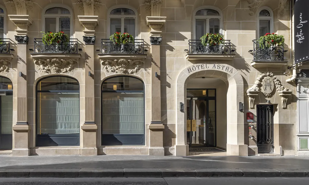 Facciata in pietra dell’Hotel Astra Opéra a Parigi, con una porta d’ingresso ad arco.