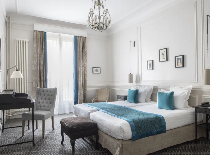 Lits d’une Chambre Twin Privilège à l’Hôtel Bradford Elysées avec draps blancs et coussins bleus