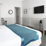 Lits d’une Chambre Twin Privilège à l’Hôtel Bradford Elysées avec draps blancs et chemin de lit bleu