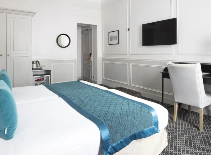Lits d’une Chambre Twin Privilège à l’Hôtel Bradford Elysées avec draps blancs et chemin de lit bleu