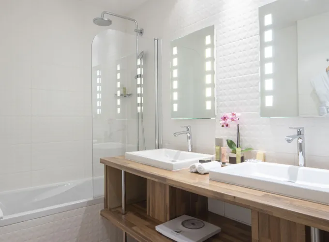 Salle de bain d’une Chambre Twin Privilège à l’Hôtel Bradford Elysées avec deux lavabos et une baignoire