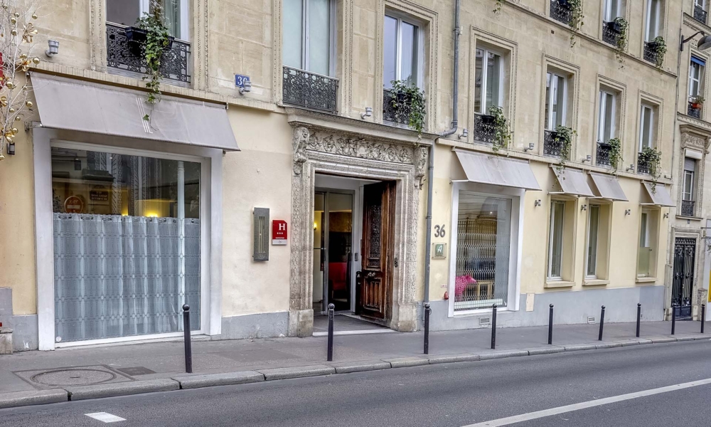 Fachada do Hotel Lorette – Astotel em Paris, com entrada ao nível da rua e porta de acesso central.