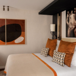 Chambre Classique de l’Hôtel Barnett à Paris avec lit double, coussins terracotta et œuvres d’art contemporaines.