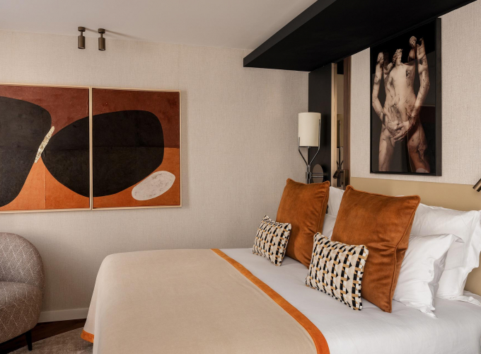 Chambre Classique de l’Hôtel Barnett à Paris avec lit double, coussins terracotta et œuvres d’art contemporaines.