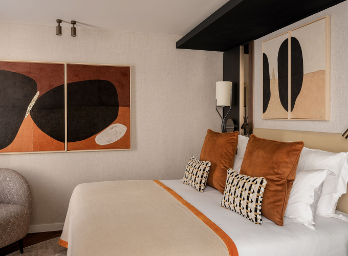 Chambre Supérieure de l’Hôtel Barnett à Paris avec lit double, coussins terracotta, fauteuil et œuvres d’art contemporaines.