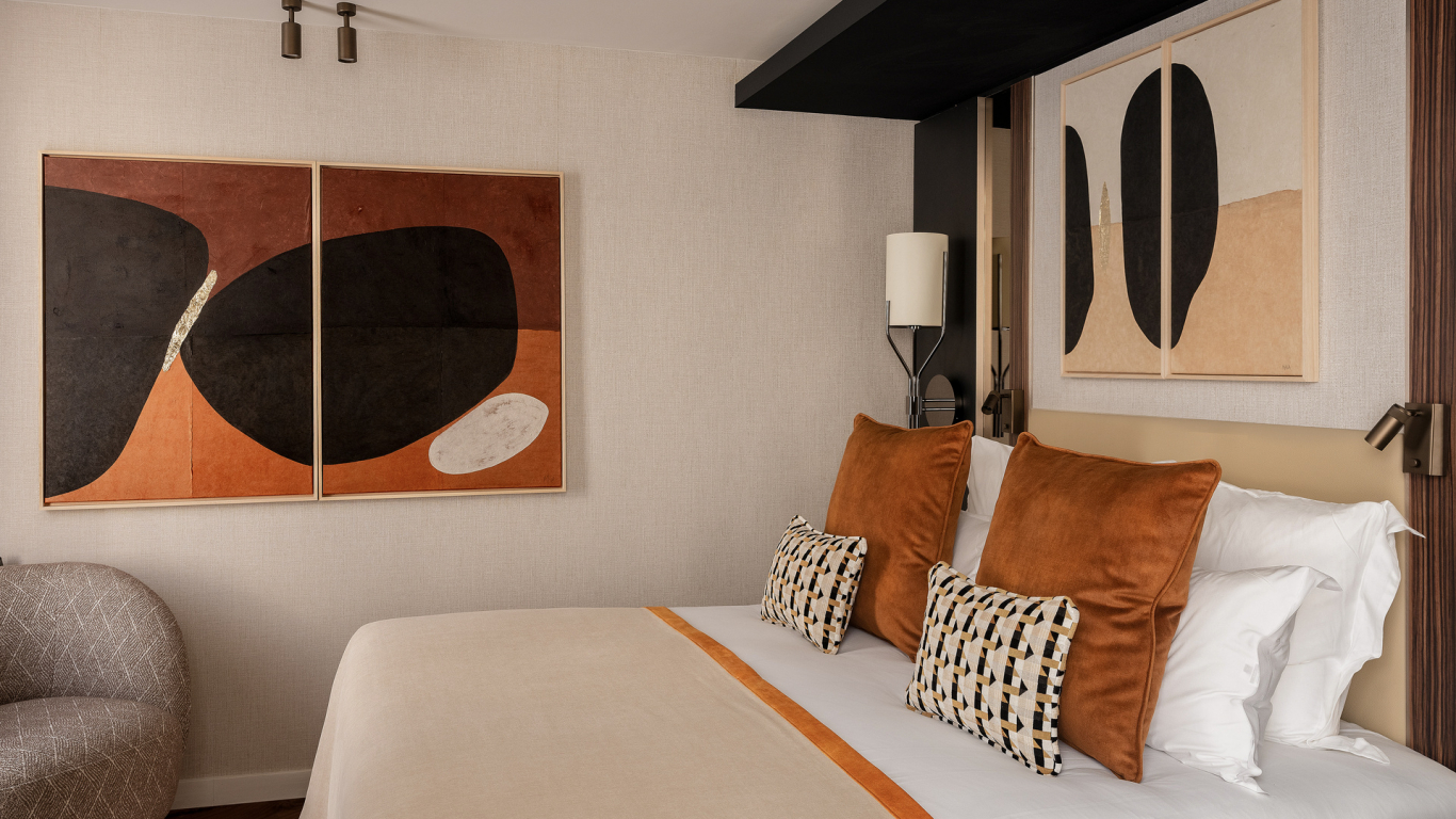 Chambre Classique de l’Hôtel Barnett à Paris avec lit double, coussins terracotta et œuvres d’art contemporaines.
