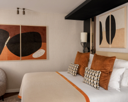 Chambre Classique de l’Hôtel Barnett à Paris avec lit double, coussins terracotta et œuvres d’art contemporaines.