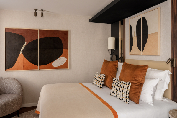 Chambre Classique de l’Hôtel Barnett à Paris avec lit double, coussins terracotta et œuvres d’art contemporaines.