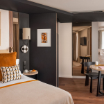 Chambre Supérieure de l’Hôtel Barnett à Paris avec lit double, coussins terracotta, fauteuil et œuvres d’art contemporaines.